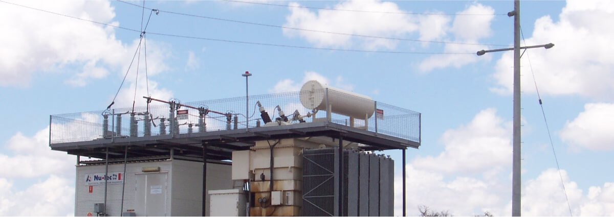 Electrical substation with various transformers and equipment, under a partly cloudy sky, illustrating the Earthing & Earth Grid Design involved in power distribution systems